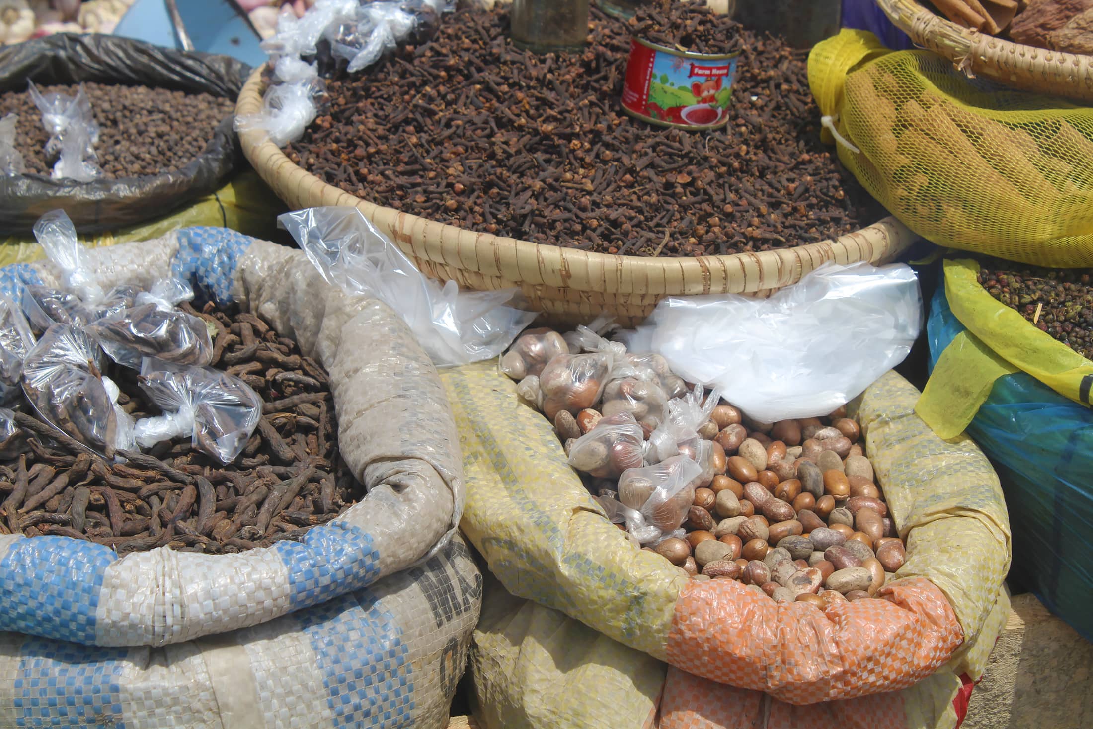 Herbs and spices for sale at a Nigerian market, sorted into baskets and sacks